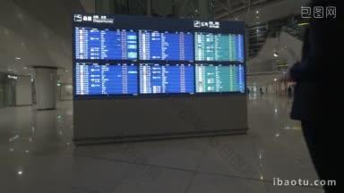 年轻女子在机场查看航班时刻表，在平板电脑上查了一些东西，然后离开